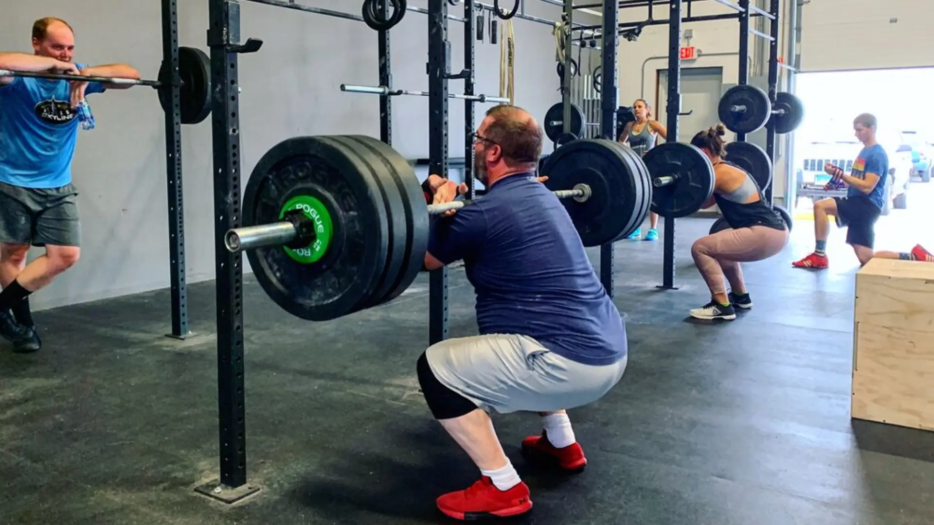 Lifters squatting heavy barbells in the racks at O.N. Athletics in Groton, CT