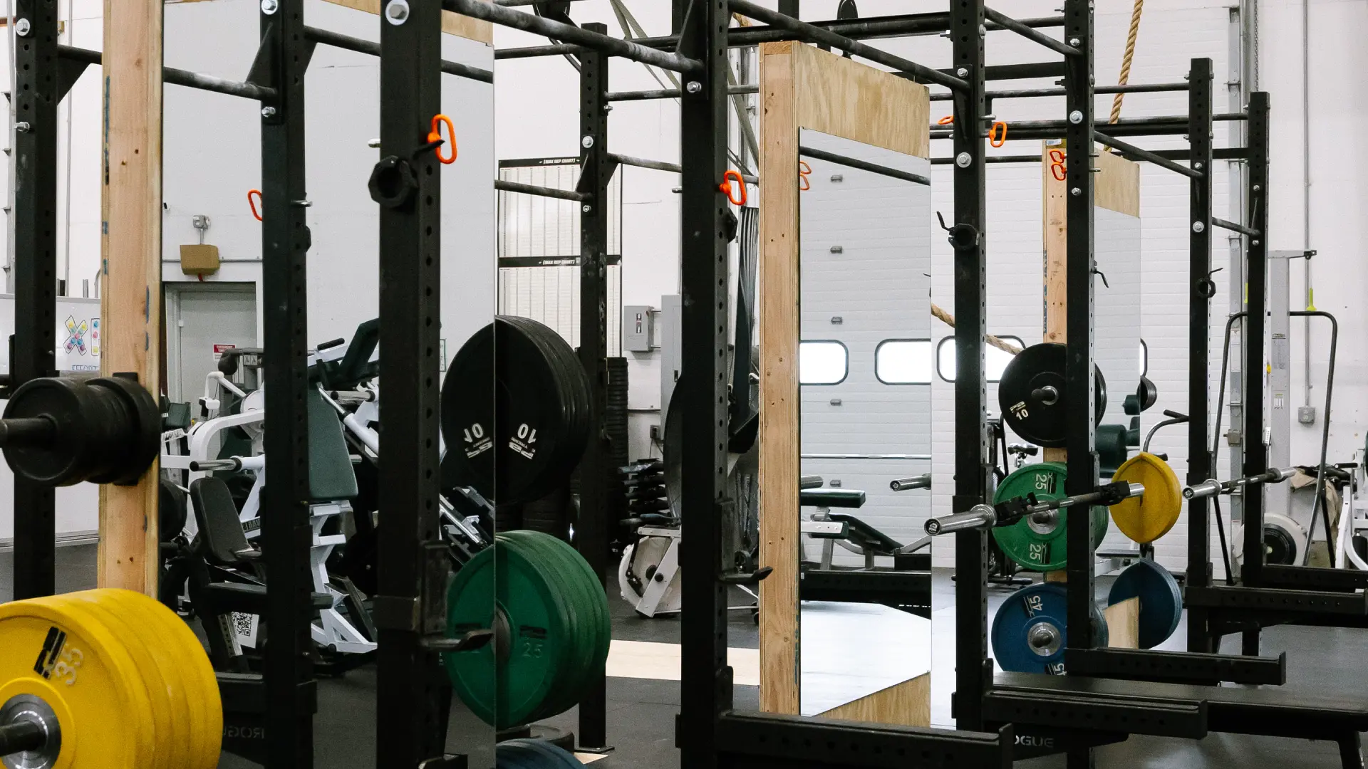 Squat racks with mirrors, bumper plates and barbells at O.N. Athletics in Groton, CT