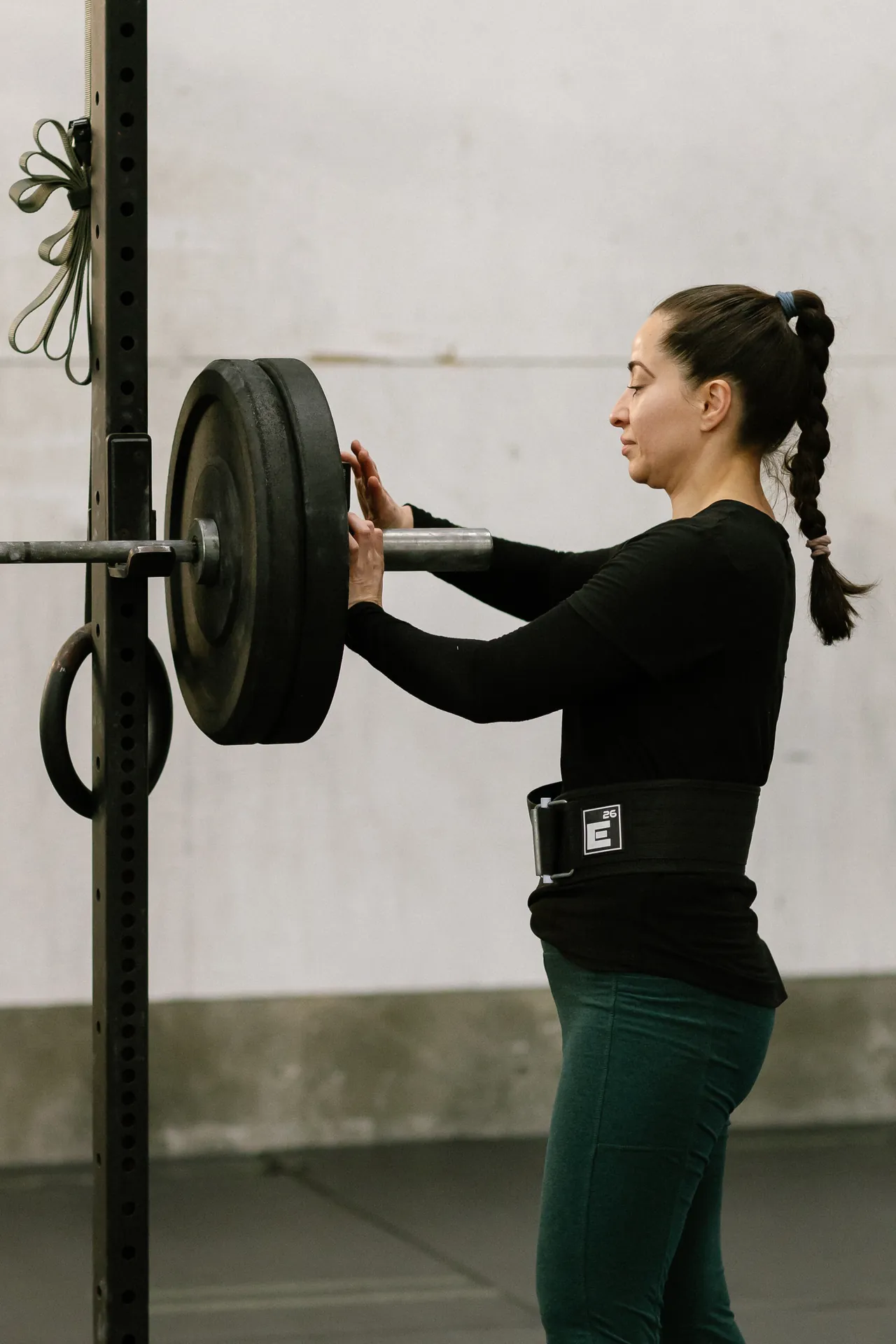 Member loading plates onto a barbell in the squat rack at O.N. Athletics in Mystic, CT